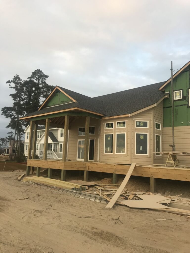 Deck and covered porch on a raised coastal home by Cas and Cal Construction